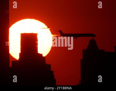 Flushing Meadow, États-Unis. 05th Sep, 2024. Les avions passent devant le soleil se couchant derrière les gratte-ciel de Manhattan depuis le sommet du stade Arthur Ashe lors des US Open Tennis Championships 2024 au USTA Billie Jean King National Tennis Center le jeudi 5 septembre 2024 à New York. Photo de John Angelillo/UPI crédit : UPI/Alamy Live News Banque D'Images