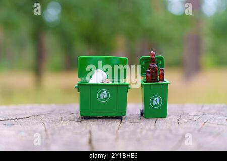 Deux bacs de recyclage verts miniatures remplis de bouteilles en plastique et en verre, illustrant l'importance de séparer les déchets. Banque D'Images