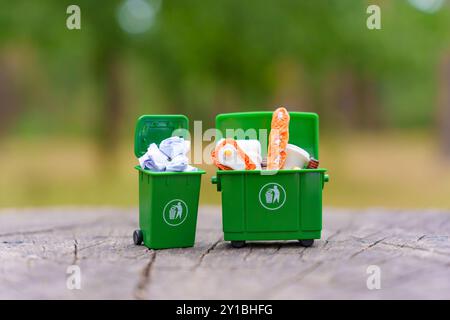 Deux poubelles miniatures vertes remplies de déchets non triés, mettant en évidence les concepts de gestion et de recyclage des déchets. Banque D'Images