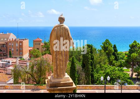 Tarragone, Espagne - 14 juillet 2024 : Statue historique de l'empereur César Auguste avec une toile de fond captivante de la côte de Tarragone et des eaux turquoises Banque D'Images