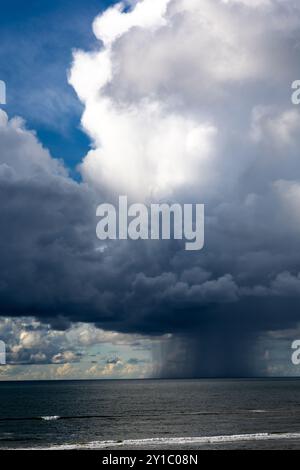 Cloudscape au-dessus de la mer peu avant un orage avec une averse de pluie descendant à l'eau Banque D'Images