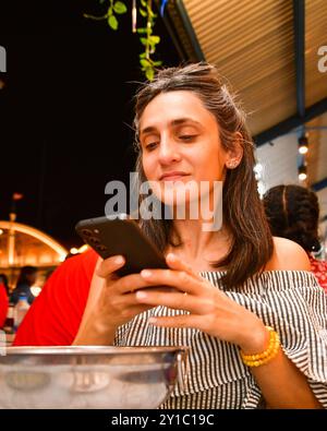 Gros plan jeune femme caucasienne tient un smartphone prenant en photo son repas de soupe de dîner du haut dans un restaurant public occupé. Contenu alimentaire des médias sociaux Banque D'Images