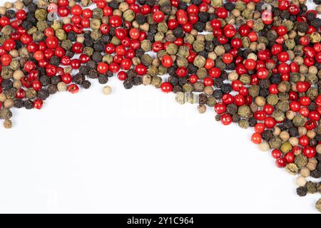 Grains de poivre rouge, vert, blanc et noir sur fond blanc, espace de copie pour le texte. Banque D'Images
