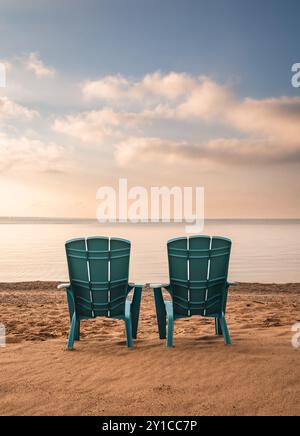 Deux chaises adirondack turquoise sur la plage de sable avec vue sur le lac en été. Banque D'Images