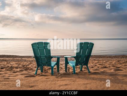 Deux chaises adirondack turquoise sur la plage de sable avec vue sur le lac en été. Banque D'Images
