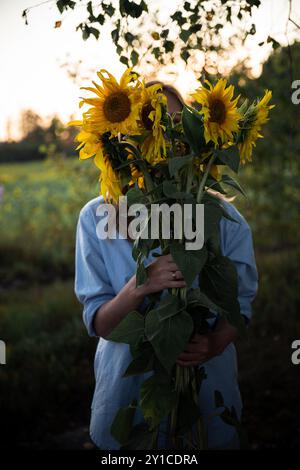 jeune femme tenant un grand bouquet de tournesols Banque D'Images