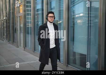 Jeune homme marchant dans une ville avec des écouteurs Banque D'Images