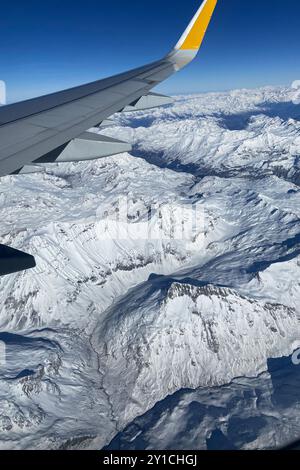 Avion volant bas au-dessus de montagnes enneigées et se préparant à atterrir à l'aéroport, vue depuis la fenêtre de l'avion de la turbine d'aile et de l'horizon Banque D'Images