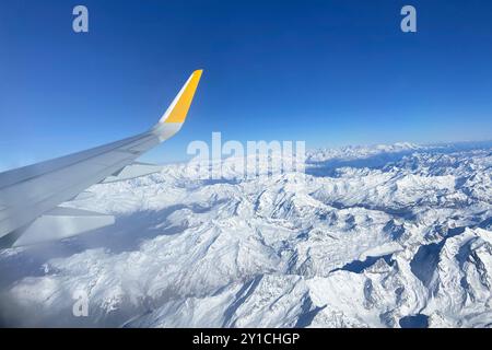 Avion volant bas au-dessus de montagnes enneigées et se préparant à atterrir à l'aéroport, vue depuis la fenêtre de l'avion de la turbine d'aile et de l'horizon Banque D'Images