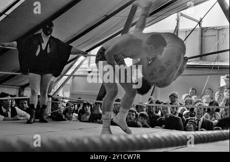 Tag Wrestling dans le spectacle de boxe Fairground Travellers de Pat McKeowen. Jack Turner (sous l'épaule de l'homme jeté, Jack regarde vers le haut) il a couru les combats au stand de boxe de Pat McKeowen. Epsom Downs, Surrey Angleterre juin 1969 1960 Royaume-Uni HOMER SYKES Banque D'Images