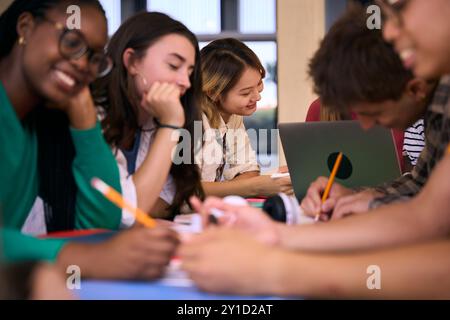 Groupe de divers étudiants universitaires Gen z se réunissant ensemble pour faire des devoirs dans l'étude du campus. Banque D'Images