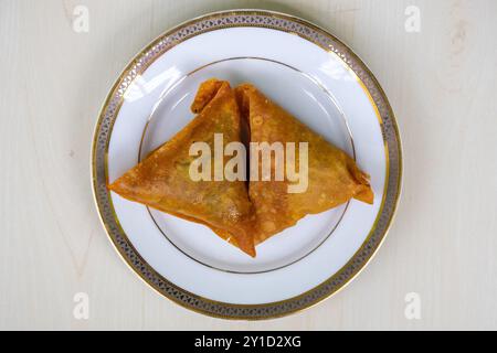 Deux samosas sur une plaque blanche. Cuisine asiatique délicieuse. Il est connu comme sambusa, singara, samose, somsa, singada, et samuza. Vue de dessus Banque D'Images