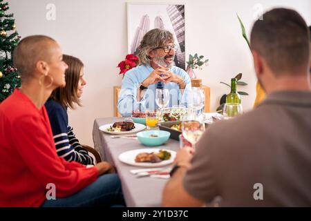 Repas de Noël de la famille caucasienne heureuse profitant ensemble assis détendu à table à la maison. Banque D'Images