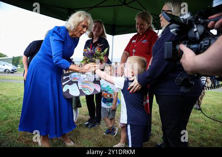 La reine Camilla, Commodore honoraire de l'Air, reçoit des fleurs des enfants des écoles maternelles locales, lors de sa visite à RAF Leeming, Northallerton, pour rencontrer le personnel de service et leurs familles et en apprendre davantage sur le soutien social qui leur est offert. Date de la photo : vendredi 6 septembre 2024. Banque D'Images