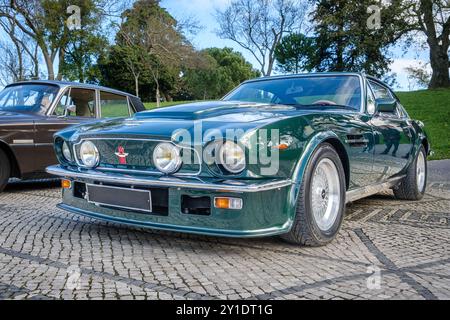 Lisbonne, Portugal - 20 janvier 2024 : Grand Tourer Aston Martin V8 Vantage vert foncé classique garée sur une route pavée, connue sous le nom de Grande-Bretagne première supercar, coupé 2 portes, avec l'emblème de l'AMOC, célébration des 75 ans de l'Aston Martin Owners Club en 2010 Banque D'Images