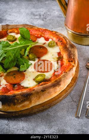 Vue de dessus de pizza napolitaine avec saucisse, poivrons jalapeno et roquette Banque D'Images