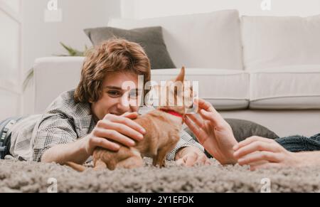 Couple gay câlin leur chihuahua sur un tapis confortable, rayonnant d'amour et de joie dans leur maison Banque D'Images