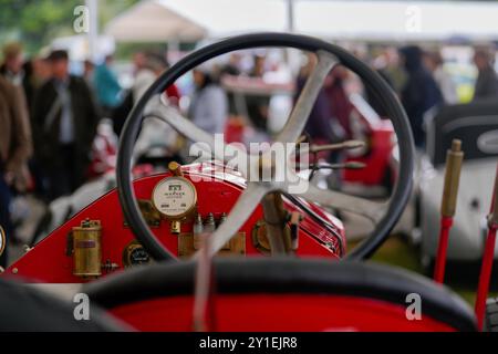 Regardant à travers le cockpit ouvert et le volant vers le tableau de bord d'une voiture vintage rouge pendant Goodwood Revival. Foule de mise au point peu profonde dans la distance. Banque D'Images