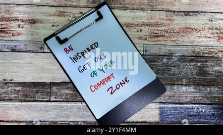Concept de Be Inspired sortez de votre zone de confort écrivez sur des papiers isolés sur fond de bois. Banque D'Images