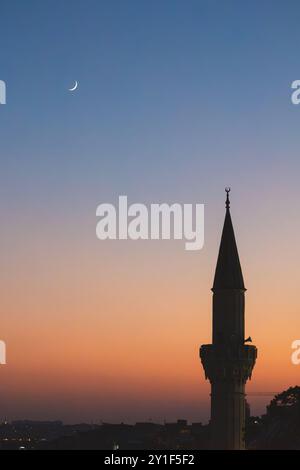 Une superbe silhouette du minaret d'une mosquée contre le ciel du soir, illuminée par la douce lueur de la lune et des étoiles pendant le Ramadan. Banque D'Images