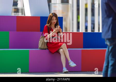 IFA 2024 Deutschland Berlin AM 05.09.2024 : eine Junge Frau sitzt am farbenfrohen IFA-logo. *** IFA 2024 Allemagne Berlin le 05 09 2024 Une jeune femme est assise près du logo coloré de l'IFA Banque D'Images