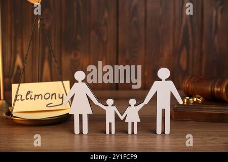 Carte avec mot pension alimentaire, figures de famille, écailles, anneaux et marteau sur table en bois Banque D'Images