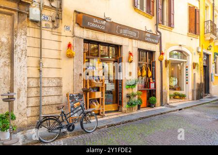 Un vélo stationné devant un marché italien traditionnel vendant des charcuteries, des fromages et du pain sur la Piazza Bra, la place centrale de Vérone, en Italie Banque D'Images