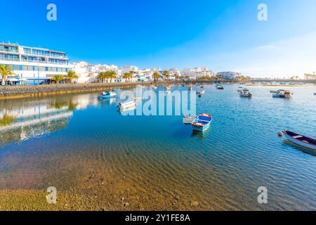 De petits bateaux de pêche colorés flottent dans la lagune d'eau de mer Charco de San Gines à la ville balnéaire espagnole d'Arrecife, Espagne, îles Canaries. Banque D'Images