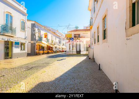 Une petite place avec des magasins, des cafés de trottoir et des marchés dans la vieille ville historique de la ville balnéaire blanchie à la chaux de Lagos, région de l'Algarve au Portugal. Banque D'Images