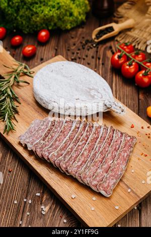 Gros plan de salami séché en tranches à bord, idéal pour les présentations gastronomiques et de charcuterie Banque D'Images