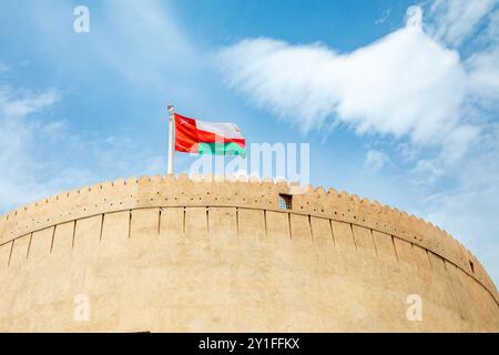 Tour principale de la forteresse citadelle arabe de Nizwa avec drapeau omanais agitant sur le dessus, Nizwa, sultanat Oman Banque D'Images