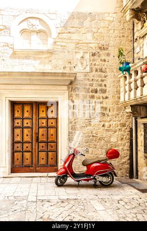 Scooter Vespa rouge dans une rue de la ville de Trogir sur la mer Adriatique, côte dalmate, Croatie Banque D'Images