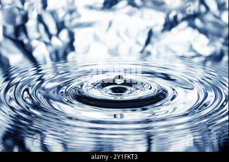 une goutte d'eau tombe à la surface de l'eau et crée des cercles concentriques, des vagues, des ondulations Banque D'Images