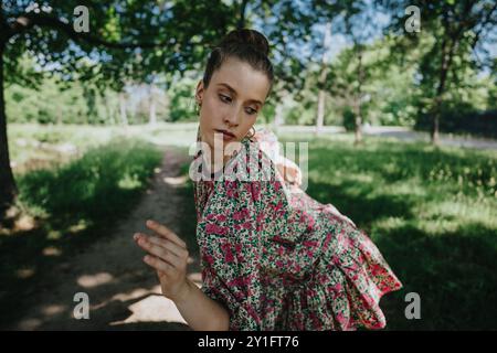 Jeune femme exécutant la danse moderne dans la nature entourée de verdure et de lumière du soleil Banque D'Images