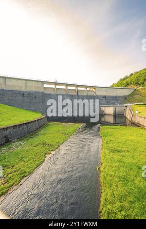 Une rivière coulant sous un grand barrage en béton, entouré d'herbe et de nature, barrage de Rappbode, montagnes du Harz, Allemagne, Europe Banque D'Images