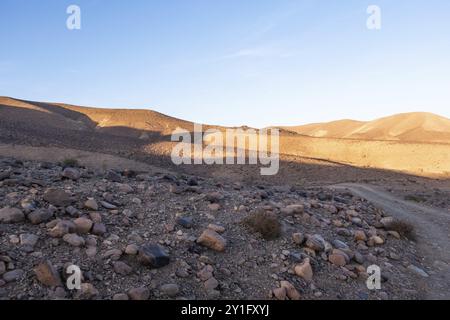 Traversée des montagnes rocheuses du deseert marocain. Vue en noir et rouge avec fond bleu ciel près de l'heure du coucher du soleil Banque D'Images