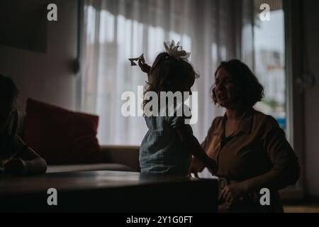 Silhouette d'une maman et d'une jeune fille partageant un moment sincère à l'intérieur Banque D'Images