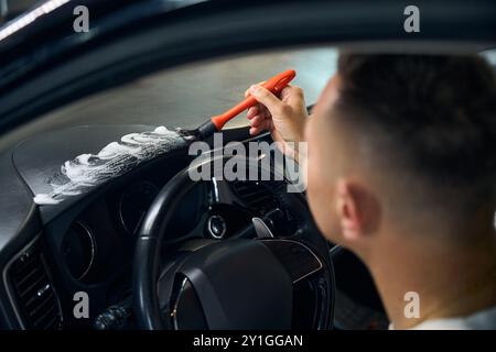 Un homme nettoie un panneau dans une voiture Banque D'Images