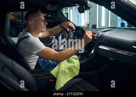 Mâle en salopette bleue effectue l'esthétique automobile Banque D'Images