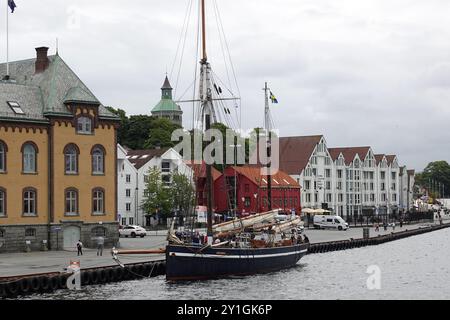 Stavanger, Norvège - 4 août 2024 le quai de Vågen à Stavanger avec de vieilles maisons et un grand voilier Banque D'Images