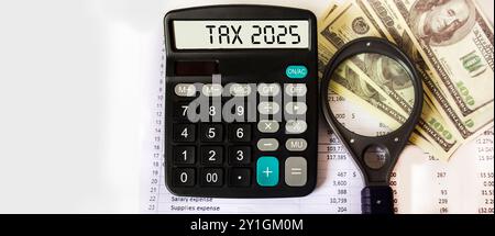 Le mot Tax 2025 sur une calculatrice. Concept des affaires et de la fiscalité. Calculatrice, devise, gros plan des billets en dollars. Banque D'Images