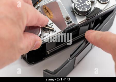 Gros plan d'une personne ouvrant le couvercle arrière pour insérer le rouleau de film dans un appareil photo reflex vintage. Banque D'Images
