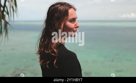 Une femme se tient devant un plan d'eau, paraissant contemplative et connectée à l'environnement naturel. Banque D'Images