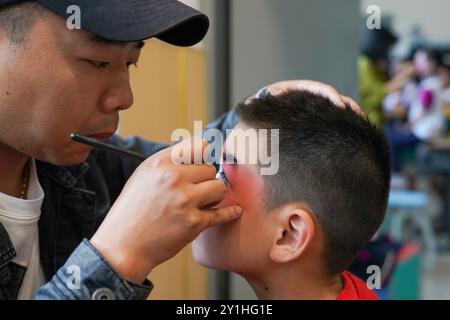 (240907) -- KUNSHAN, 7 septembre 2024 (Xinhua) -- Zhou Jie, professeur à plein temps de la « classe de formation de l'Opéra de Kunqu », aide un élève à préparer le maquillage avant une représentation dans une salle de formation de l'école primaire Shipai Center de Kunshan dans la ville de Kunshan, province du Jiangsu, dans l'est de la Chine, 31 mai 2024. Né en 1995 et élevé dans la ville de Kunshan, dans la province du Jiangsu de l'est de la Chine, Zhou Jie a rempli ses souvenirs d'enfance avec l'opéra de Kunqu à chaque festival et célébration. La ville de Kunshan est le lieu de naissance de l'Opéra de Kunqu, qui est répertorié par l'Organisation des Nations Unies pour l'éducation, la science et la culture Banque D'Images