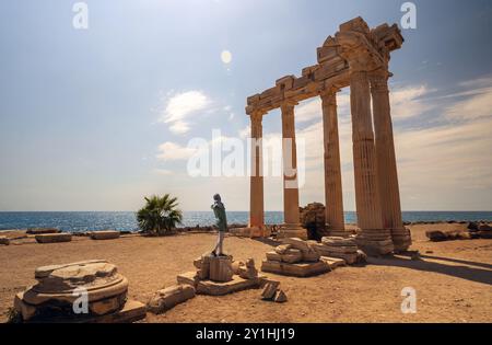 Une femme en burka posant contre une vue imprenable sur les ruines du temple d'Apollon à Side, en Turquie, avec la mer Méditerranée en arrière-plan. Banque D'Images