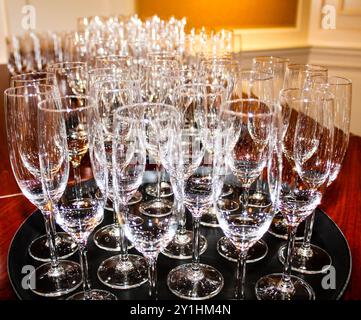 Une collection de verres étincelants propres disposés soigneusement sur un plateau, avec différents types de verres, y compris des flûtes à champagne et des verres à vin, s. Banque D'Images