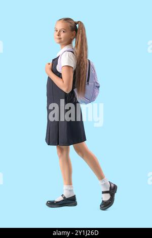 Petite fille mignonne en uniforme scolaire sur fond bleu Banque D'Images