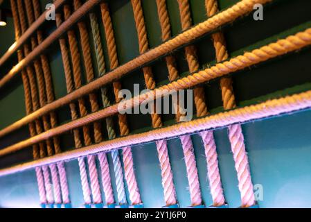 Cordes croisées accrochées au mur comme décoration abstraite. Design d'intérieur original fait maison avec fond vert et lumières LED coloufsul, le ro Banque D'Images