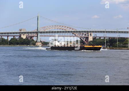 Remorqueur poussant la barge à travers la section dangereuse Hell Gate de l'East River dans le Queens, New York Banque D'Images