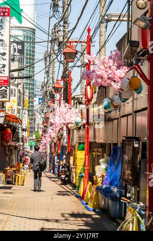 Salaryman marchant le long de Omoide Yokocho, une ruelle animée et nostalgique remplie de dîners traditionnels japonais izakaya et de nourriture de rue. Ciel bleu ensoleillé. Banque D'Images